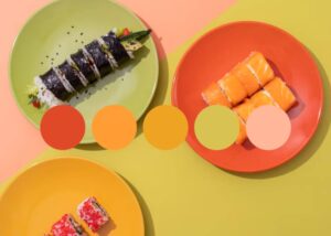 An assortment of sushi rolls on vibrant plates, featuring colorful sushi on green and orange dishes against a yellow background.