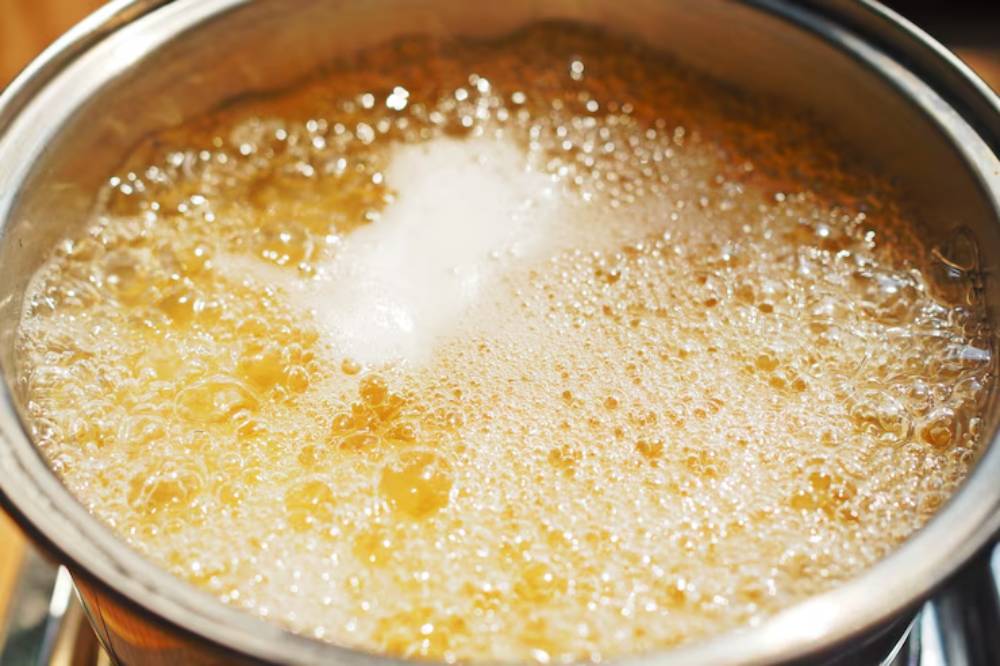 Close-up of a pot bubbling with boiling liquid, showing energetic bubbles and steam rising from the surface.